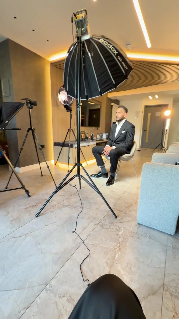 Dr Adeel Ali seated on set with the camera, lighting and filming setup visible